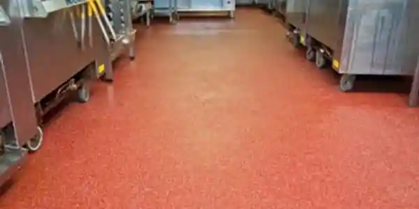 A kitchen with red floor and metal cabinets.